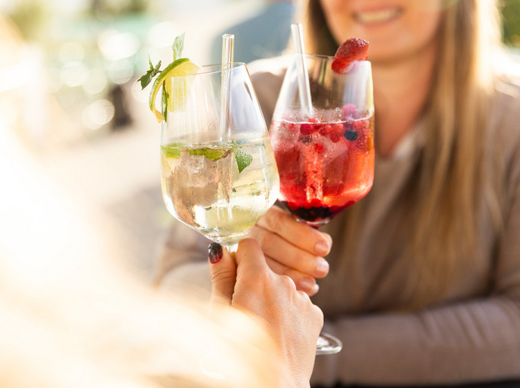 Zwei Frauen stoßen mit Cocktails an. 