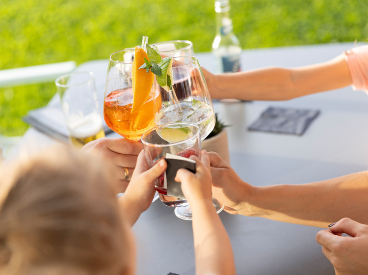 Mehrere Personen stoßen mit Getränken in Gläsern an.