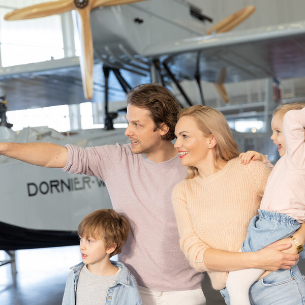Familienausflug in die Luftfahrtgeschichte Familie erkundet eine Ausstellung mit historischen Flugzeugen im Dornier Museum.