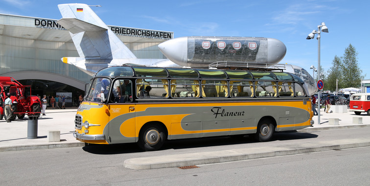 Ein gelber Shuttlebus steht vor einem Flugzeug auf dem Rollfeld.