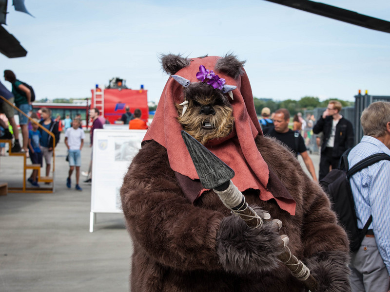 Eine Person in Star-Wars-Verkleidung im Vordergrund und mehrere Personen im Hintergrund auf dem Rollfeld.