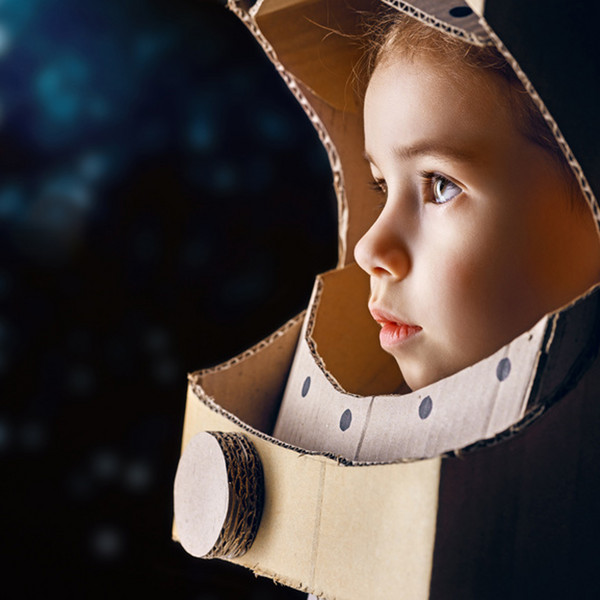 Kind in gebasteltem Astronautenkostüm schaut in die Ferne